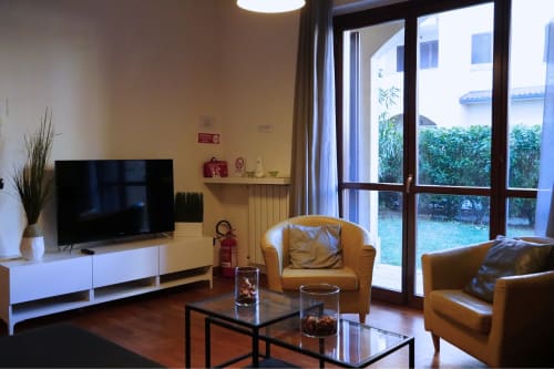 Soggiorno moderno nell'Appartamento Roma 2 della Collezione THE V, Turate, con sedute in pelle color sabbia, TV e vista sul giardino