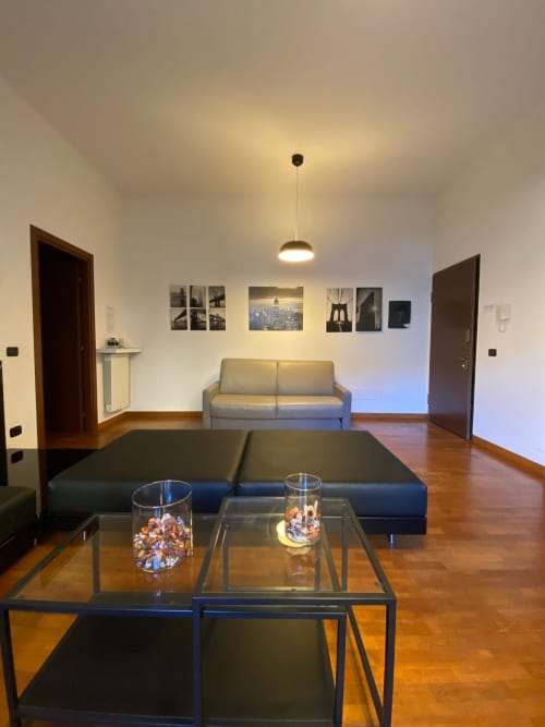 Soggiorno moderno nell'Apartment Roma 2 di THE V Collection a Turate, con tavolino in vetro, divano letto nero e divano grigio