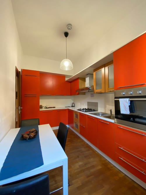 Cucina moderna rossa con tavolo da pranzo nell'Appartamento Roma 2 di THE V Collection, Turate