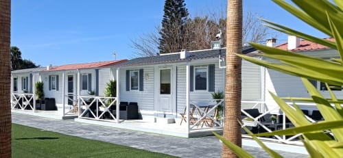 Modern white bungalow with terrace at Bungalow Buda Beach resort in Chipiona, featuring garden views and palm trees