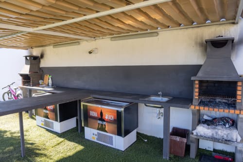 Bungalow outdoor kitchen and dining area at Buda Beach Chipiona with barbecue, sink, and shaded terrace