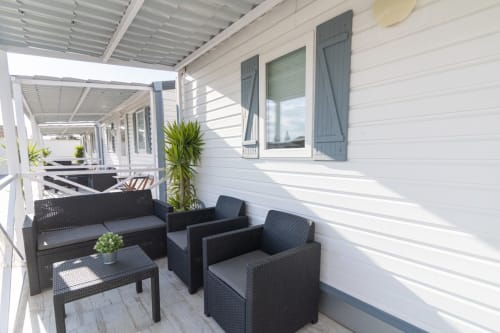 Modern terrace at Bungalow Buda Beach with black rattan seating, potted plants, and white pergola overlooking the garden