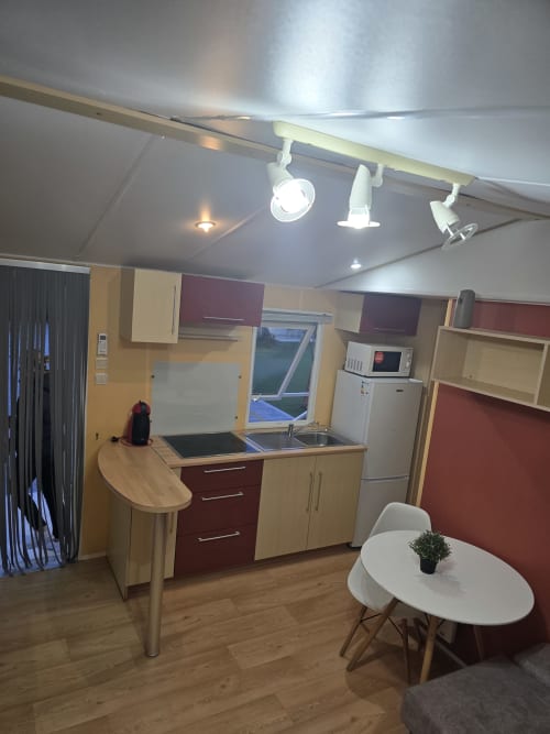 Modern kitchen and dining area in Bungalow D at Buda Beach hotel in Chipiona with wooden cabinets, stove, sink, and white