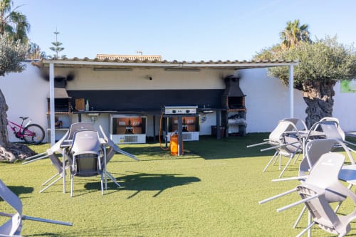 Bungalow Buda Beach garden area with lounge chairs, dining setup, and beachfront bungalow in Chipiona