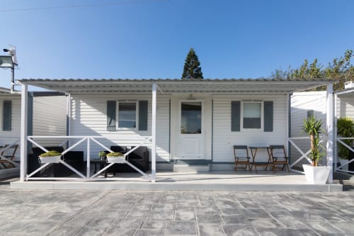 White bungalow at Buda Beach hotel in Chipiona with terrace, lounge chairs, and garden view