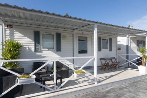 Modern white bungalow at Buda Beach Chipiona with terrace, lounge seating, and garden views under clear skies