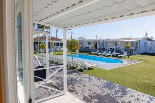 Bungalow Buda Beach terrace view overlooking pool, loungers, and garden in Chipiona, Spain