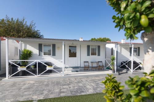 Modern white bungalow with terrace, black railings, and garden view at Bungalow Buda Beach in Chipiona