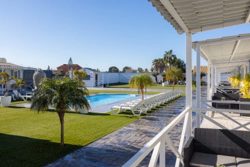 Bungalow buda beach pool area in Chipiona with loungers, palm trees, terrace, and garden views