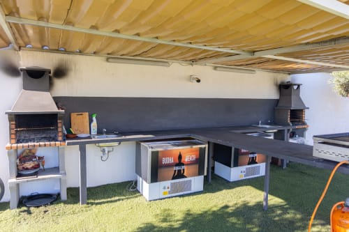Zona de barbacoa al aire libre en Bungalow Buda Beach, Chipiona, con parrillas integradas, encimera de cocina y asientos de jardín