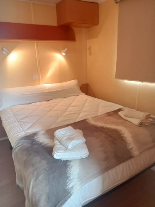 Acogedora habitación en Bungalow Buda Beach, Chipiona, con cama queen, ropa de cama blanca, toallas dobladas e iluminación cálida