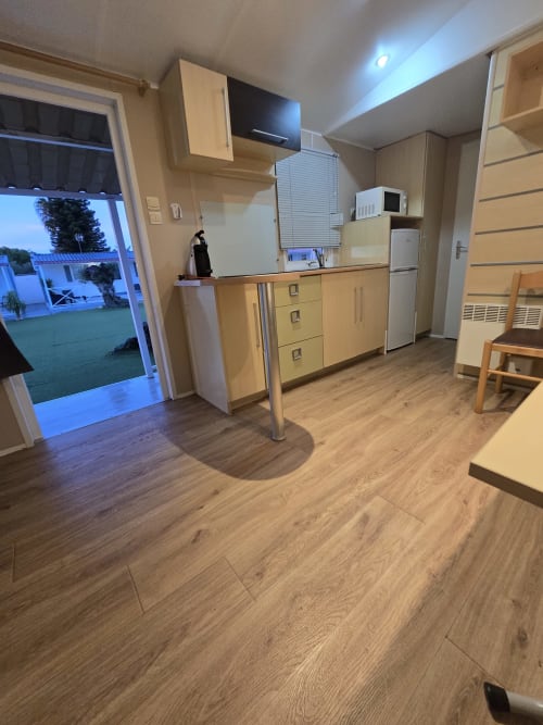 Modern kitchen and living area in Bungalow J at Buda Beach hotel, Chipiona with wooden flooring and garden view door