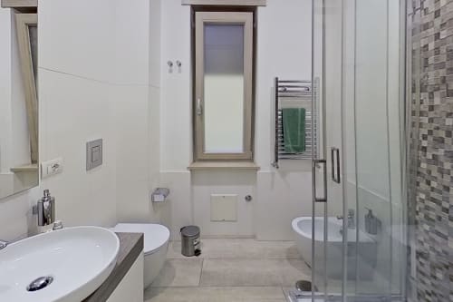 Baño moderno en Museo19 B&B de Nápoles con lavabo blanco, inodoro, toallero calefactable y cabina de ducha de cristal