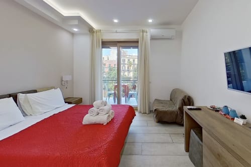 Habitación doble Museo19 en Nápoles con colcha roja, balcón con vistas a la ciudad, TV y comodidades modernas
