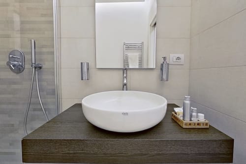 Baño moderno en el Museo19 Naples B&B con lavabo blanco, mueble de madera oscura y paredes con azulejos neutros