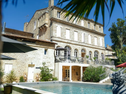 Pavillon Des Millesimes luxury cottage in Lussac with stone facade, pool view, and manicured gardens under blue sky