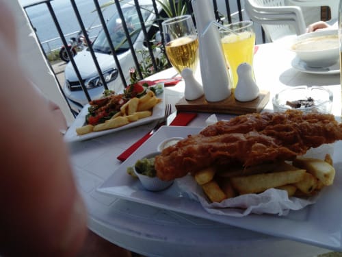 Seaside dining at Grouse Lodge: crispy fish and chips with golden fries, fresh salads, and white wine glasses overlooking