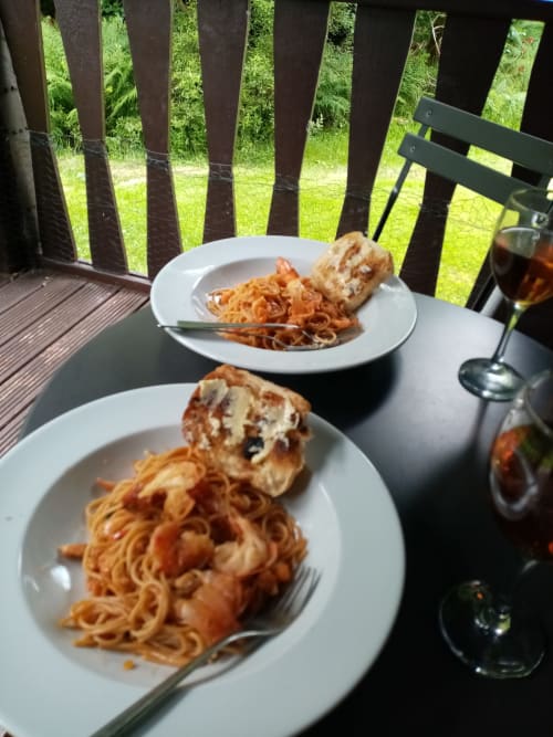 Two plates of pasta with garlic bread at Grouse Lodge in Dunoon, served outdoors with drinks