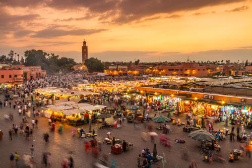 Marché Jemaa el-Fnaa au coucher de soleil à Marrakech avec la Mosquée Koutoubia, un souk animé et la foule