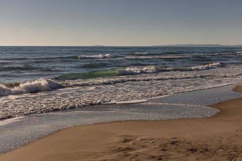 Plage de sable avec vagues et collines côtières près du Prieuré Notre-Dame à Montfrin, France