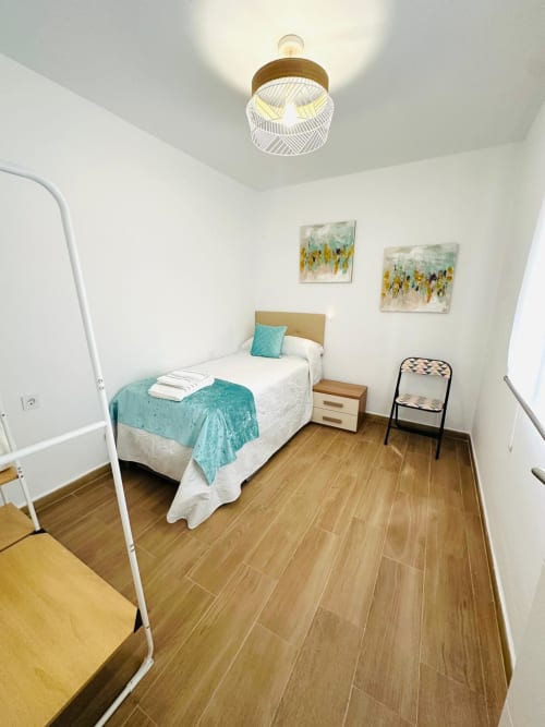 Dormitorio luminoso en Mérida con acentos turquesas, pisos de madera y moderno aplique de techo