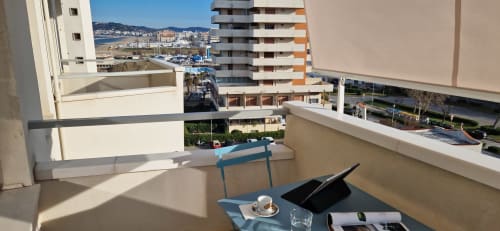 Balcony with sea view at Lamar Suites Seafront Apartments, Misano Adriatico. Table with coffee and laptop overlooking harbor.