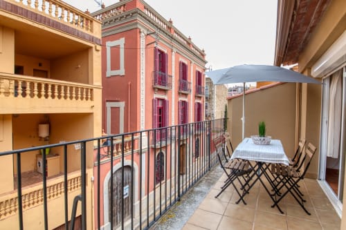 Terrasse de l'hôtel Finques Garcia Enrich à Palafrugell avec table à manger, parasol et vues sur l'architecture espagnole colorée