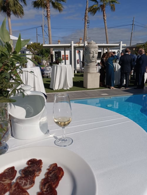 Evento junto a la piscina en Bungalow Buda Beach de Chipiona con mantelerías blancas, estatua de Buda y servicio de vinos