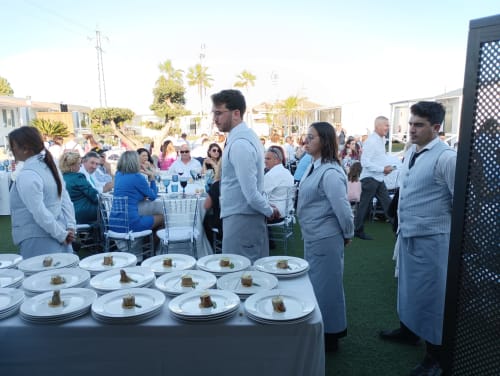 Personal de catering sirve platos en evento al aire libre, Bungalow Buda Beach, Chipiona