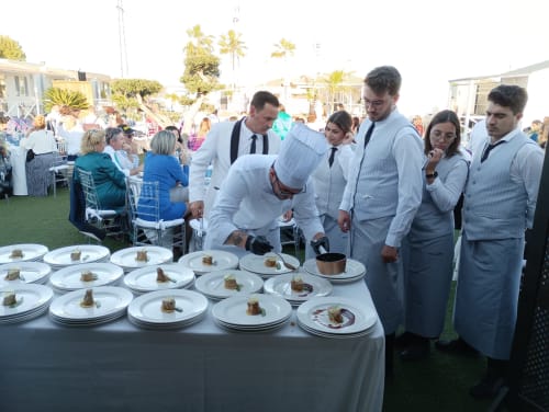 Chef preparando platos gourmet en evento frente al mar de Bungalow Buda Beach en Chipiona con personal e invitados