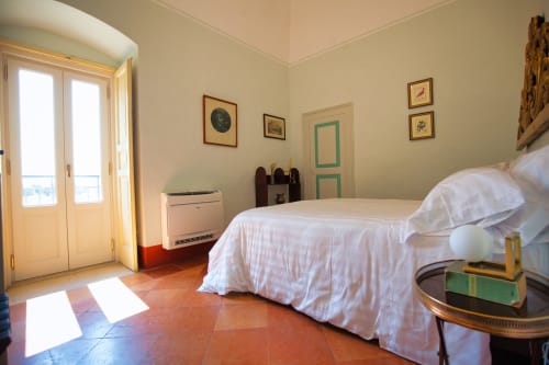 Camera luminosa di Villa Ceci ad Andria con letto bianco, pavimento in cotto e accesso al balcone con vista