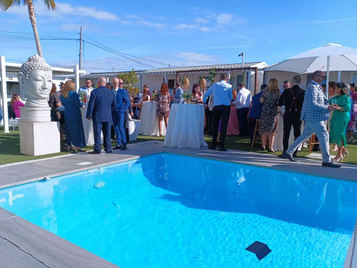 Evento junto a la piscina en Bungalow Buda Beach, Chipiona, con invitados en traje de gala conviviendo al lado de la piscina