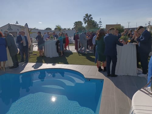 Huéspedes disfrutando de un evento junto a la piscina en el hotel Bungalow Buda Beach de Chipiona, España, con recepción de cócteles