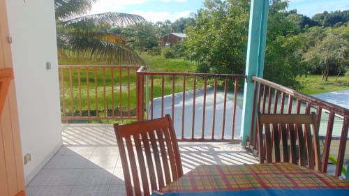 Terrasse cottage Caribgites à Sainte-Anne avec chaises en bois, vue sur le jardin et environnement tropical luxuriant