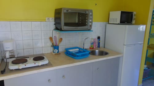 Cuisine cottage à Caribgites avec armoires blanches, murs jaunes, cuisinière compacte, évier, four grille-pain et micro-ondes