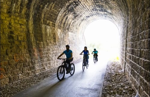 Trois cyclistes traversant un tunnel en pierre historique près de Labastide-Rouairoux, France à Bastide du Thoré