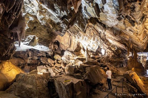 Intérieur de grotte avec stalactites et visiteur explorant les formations rocheuses près de Labastide-Rouairoux