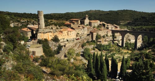 Village médiéval de Labastide-Rouairoux perché sur une colline avec ses maisons en pierre, sa tour et son pont voûté