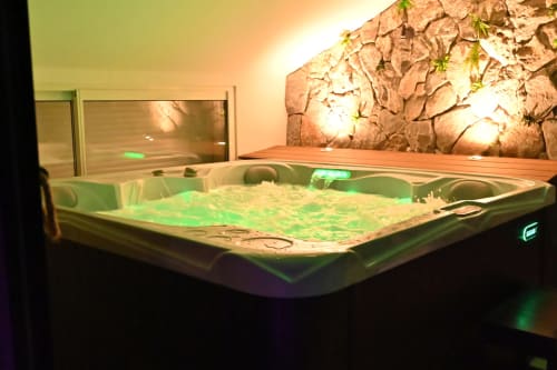 Spa luxueux de l'hôtel Accolade à Châteaudun avec éclairage ambiant vert et fond en pierre