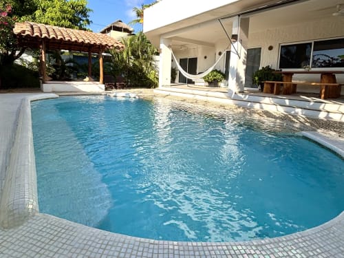 Piscina turquesa con deck de azulejos blancos en Casa Calilla, Puerto Escondido, México. Frente de playa moderno