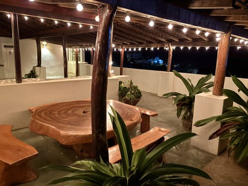 Patio exterior iluminado de Casa Calilla, Puerto Escondido, con muebles de madera y plantas tropicales bajo luces decorativas