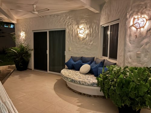 Patio exterior iluminado de la cabaña Casa Calilla en Puerto Escondido con cama redonda, cojines azules, plantas en macetas y