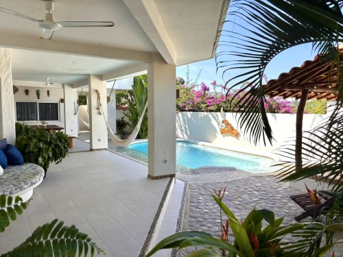 Patio de la cabaña Casa Calilla con piscina privada, hamaca, plantas tropicales y vista al mar en Puerto Escondido
