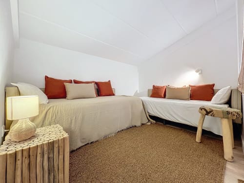 Dormitorio luminoso en la casa La Bella Lola en L'Estartit con dos camas, almohadas rojo herrumbre y muebles neutros sobre beige