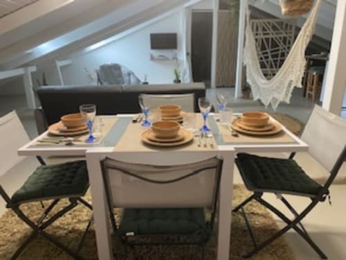 Salle à manger moderne avec table dressée, ouverte sur le séjour dans le Loft cosy et lumineux.