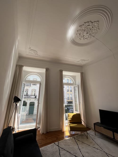 Elegant Lisbon apartment living room with ornate ceiling, tall windows, parquet floors, and city views
