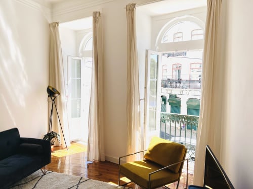 Bright Lisbon apartment living room with arched doors opening to garden view, modern furnishings, and parquet flooring