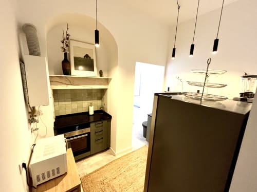 Modern kitchen with black countertops, stainless steel oven, pendant lights, and breakfast bar in Royal Prince Garden