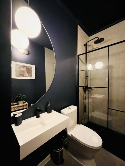 Modern bathroom in Royal Prince Garden Apartments, Lisboa, with dark walls, round mirror, white sink, toilet, and enclosed