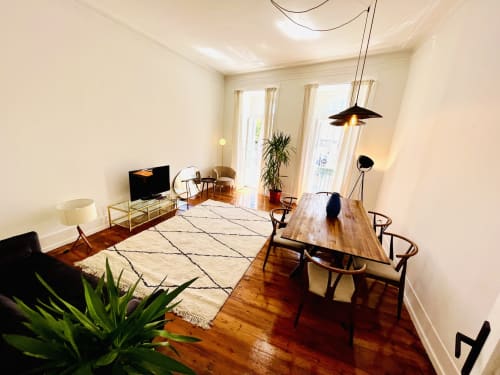 Modern apartment living room with dining table, wooden floors, and garden view in Lisboa's Royal Prince Garden Apartments